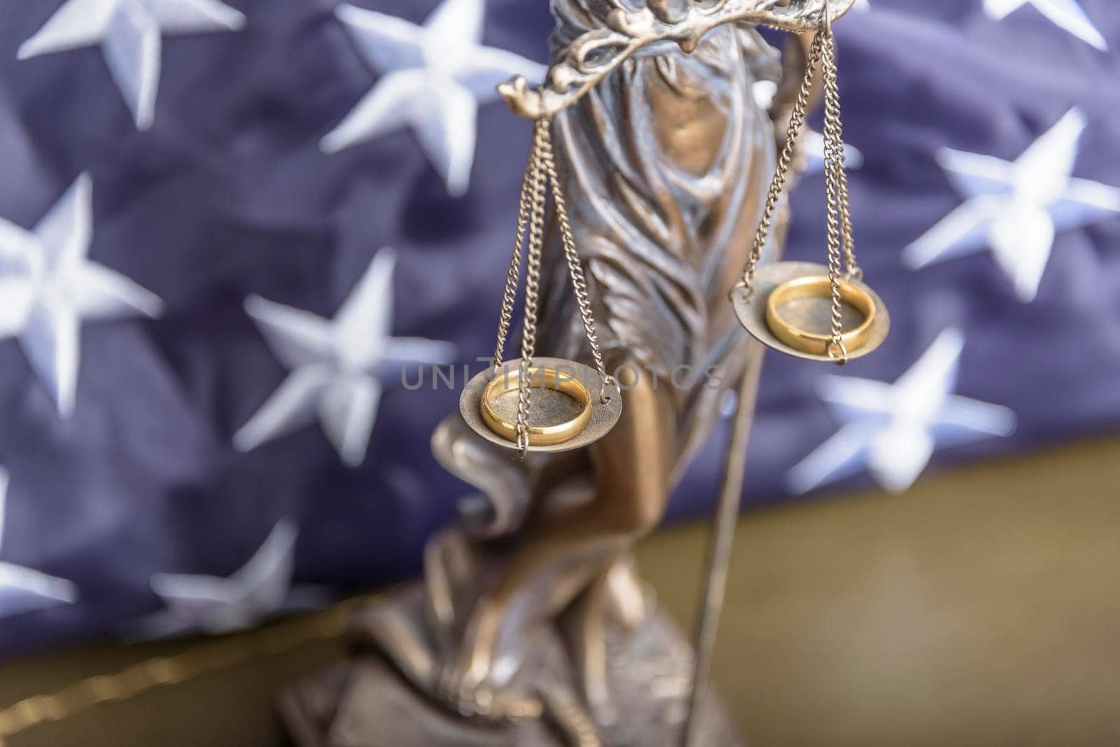 The statue of justice Themis or Iustitia, the goddess of justice blindfolded against a flag of the United States of America, as a legal concept