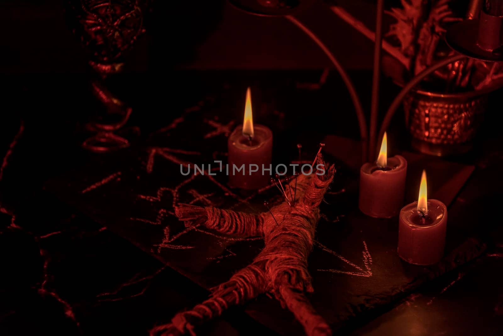 Voodoo Magic concept. Voodoo doll studded with needles with pierced rag heart on pentagram and around burning candles. Spooky or eerie magical esoteric ritua. by jbruiz78