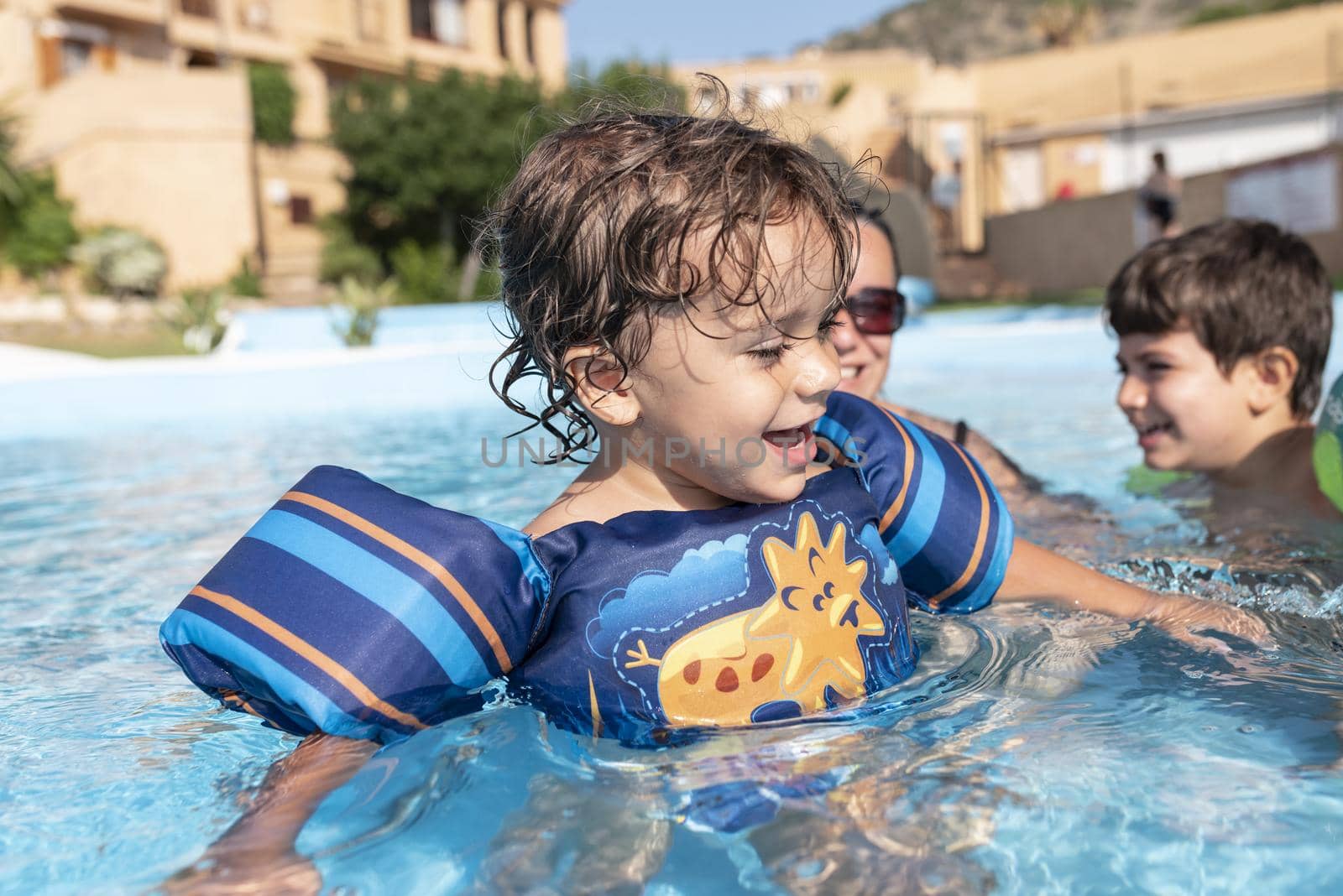 Single-parent family playing in the swimming pool. Summer arrives in the northern hemisphere