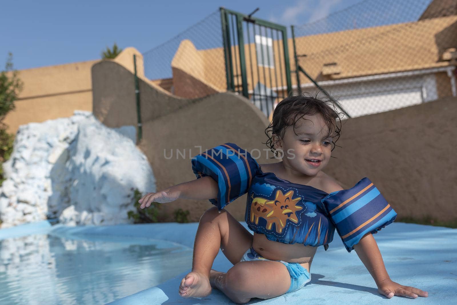 Toddler plays in the pool with children's floats. Summer arrives in the northern hemisphere