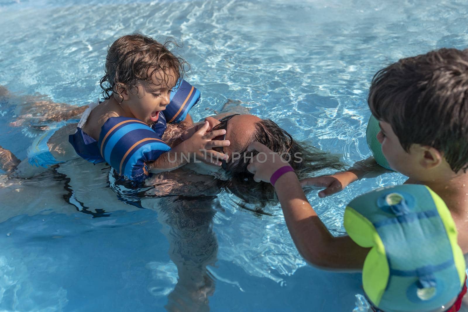 Single-parent family playing in the swimming pool. Summer arrives in the northern hemisphere