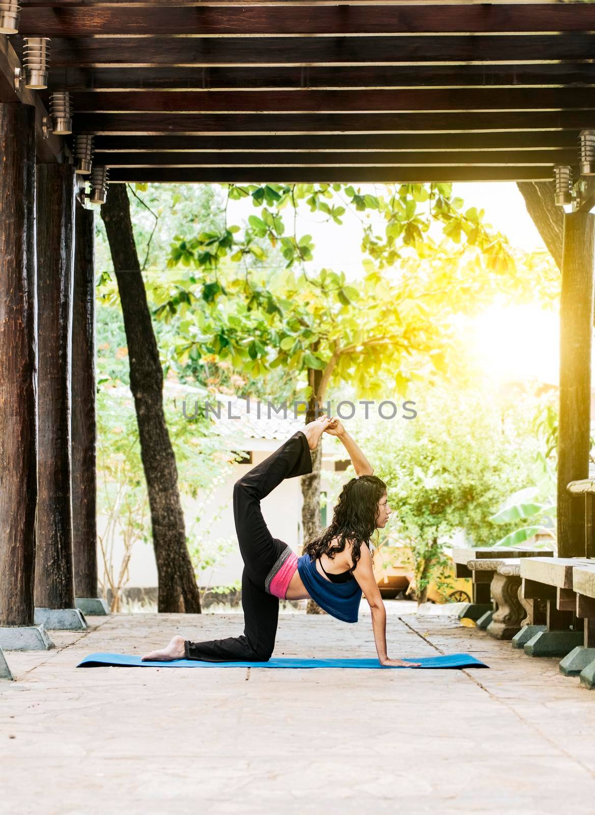 Woman doing quadriceps yoga outdoors, girl doing yoga and quadricep stretching fitness by isaiphoto