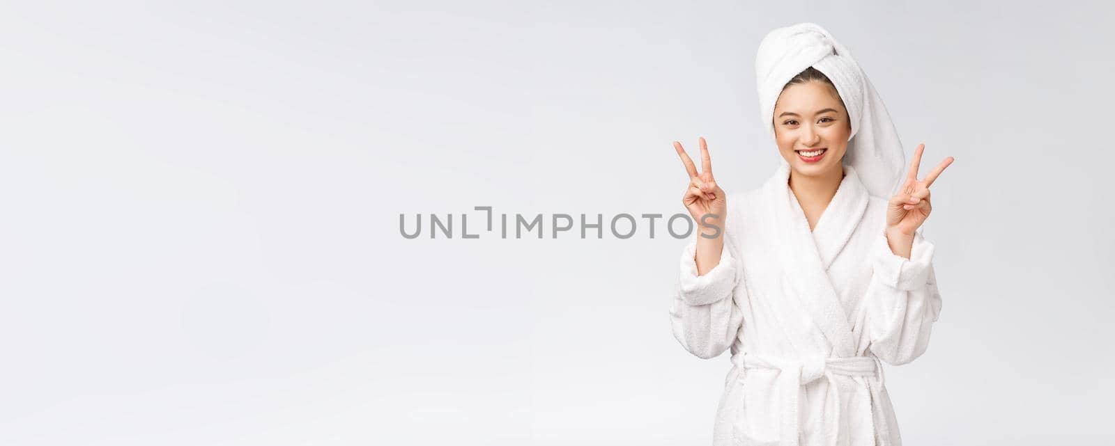 Beautiful asian woman showing peace sign or two finger with happy feeling. Isolated over white background. by Benzoix