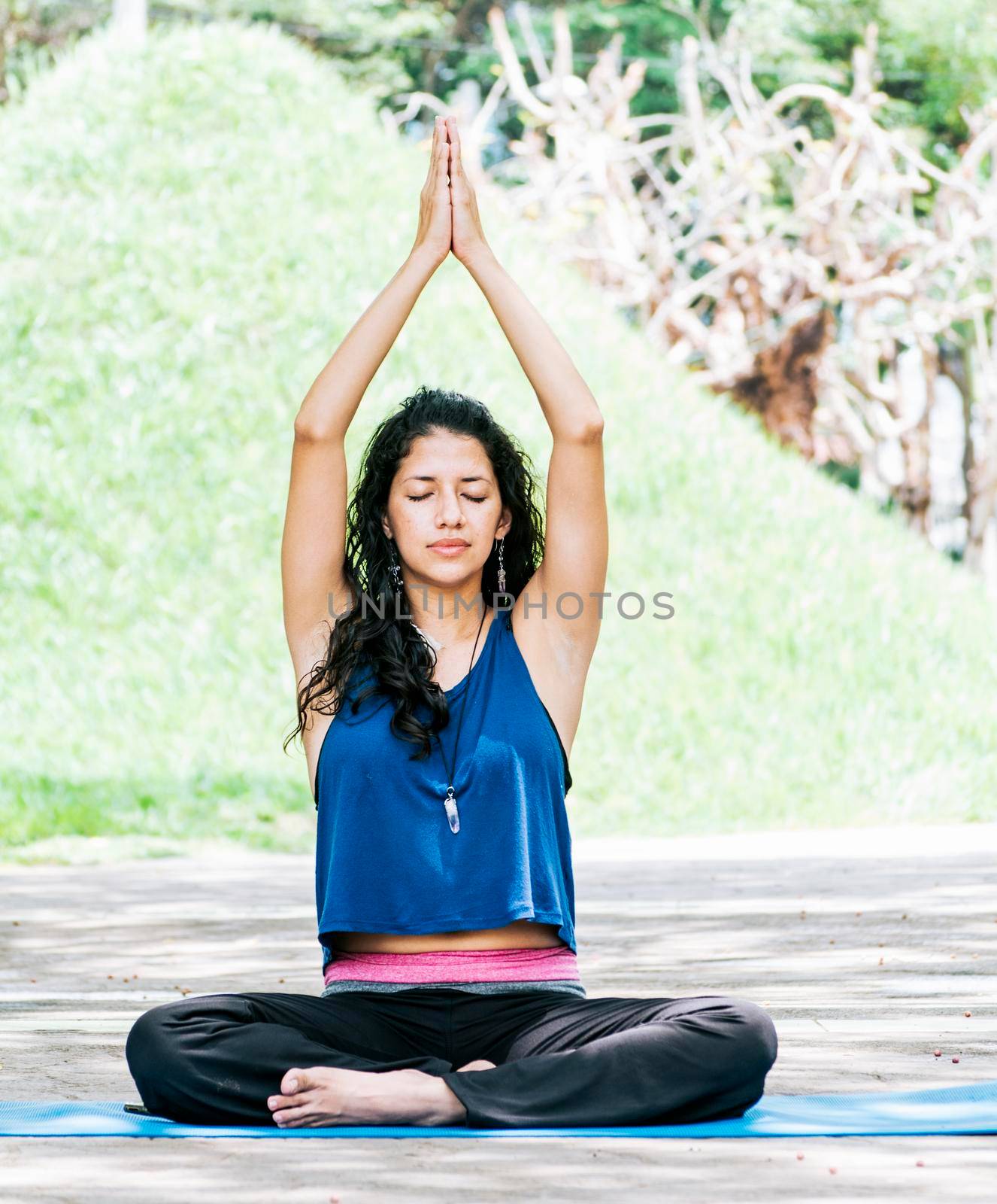 A girl sitting doing meditation yoga outdoors, a woman doing meditation yoga raising her hands up, a young woman doing yoga with her eyes closed.