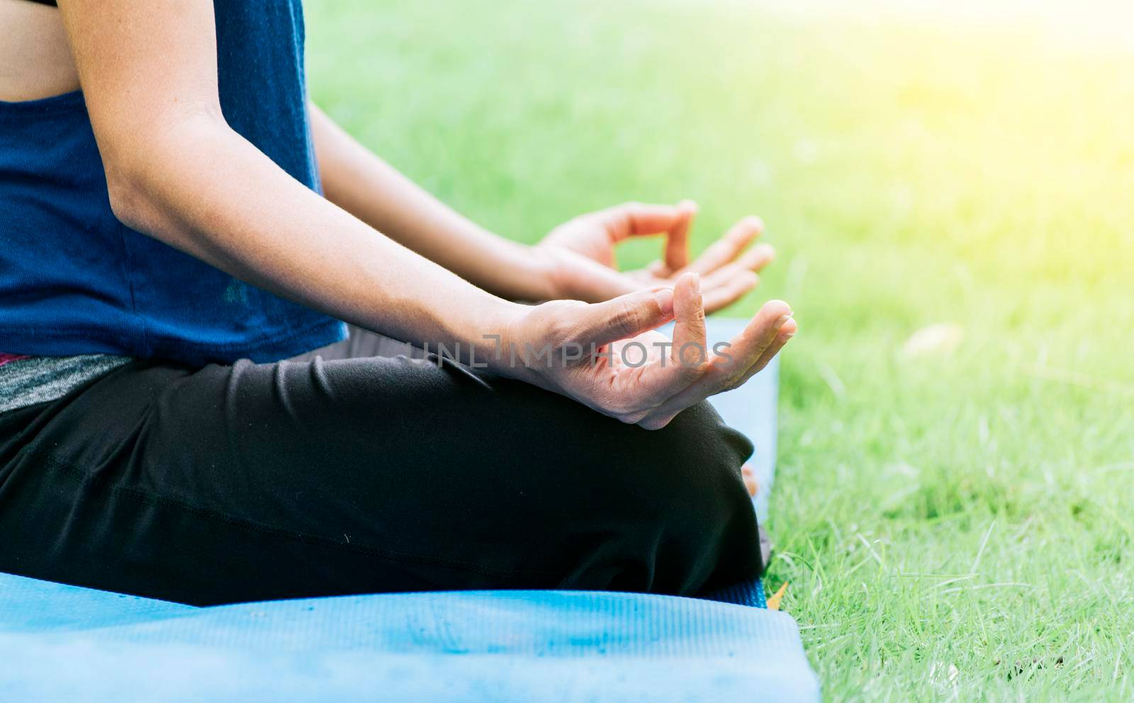 Close up of hands of a girl doing meditation yoga outdoors, Close up of hands doing yoga on the grass by isaiphoto