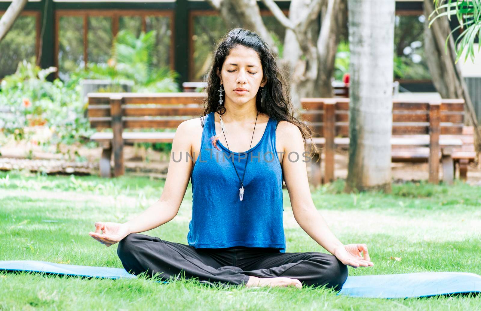 A girl sitting doing meditation yoga outdoors, Woman doing yoga outdoors, a young woman doing yoga with closed eyes. by isaiphoto