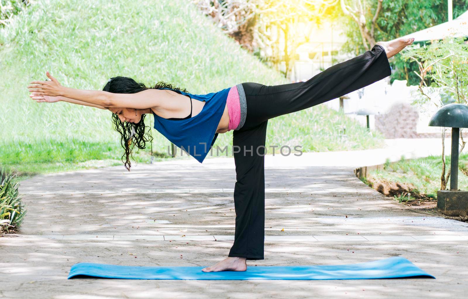 Woman doing warrior III yoga outdoors, girl doing Virabhadrana III yoga, young woman doing yoga outdoors, warrior III yoga concept by isaiphoto