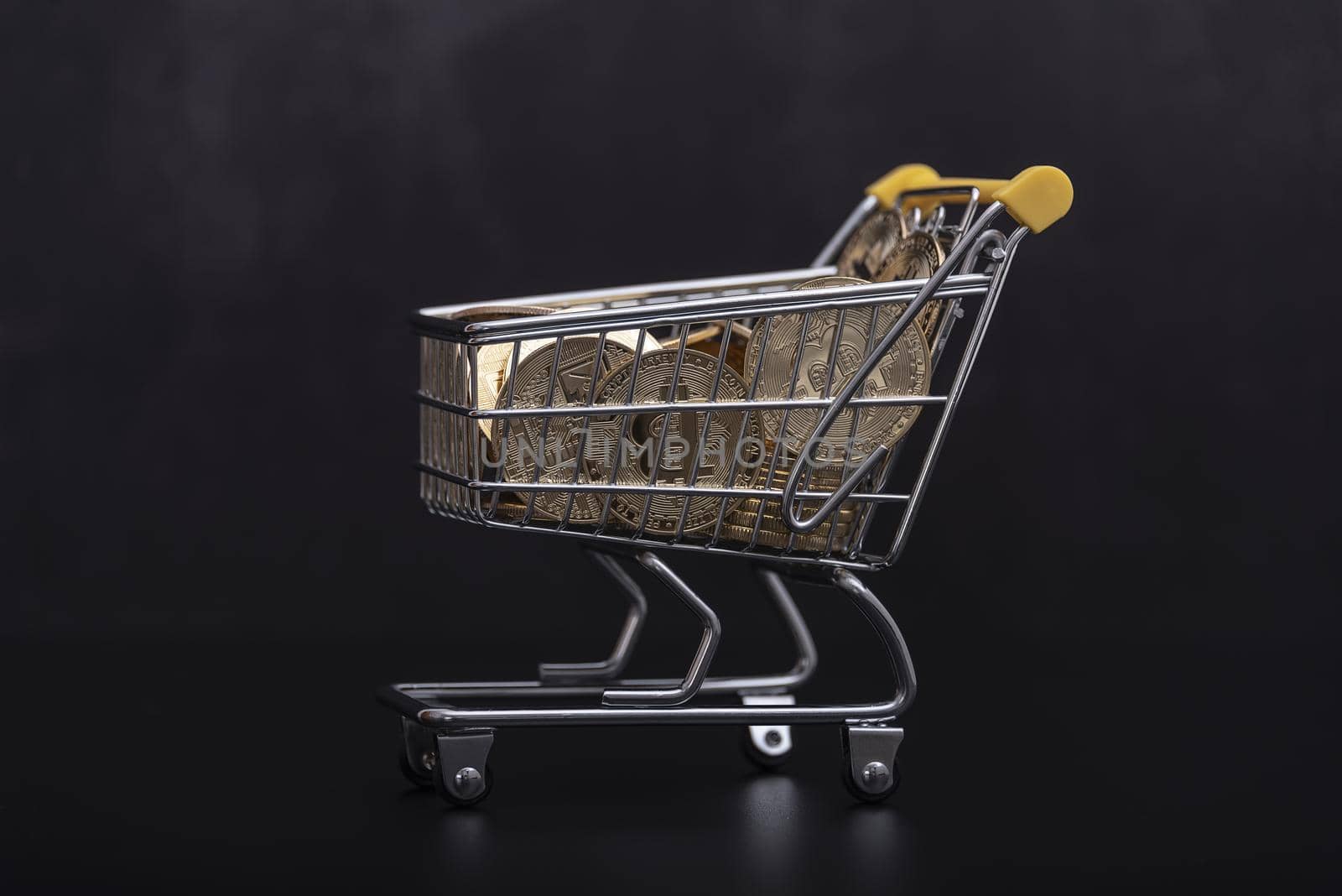 Side view of bitcoin and shopping cart on black background. Buying or selling the cryptocurrency concept. Virtual money, cryptocurrency. E-commerce concept. by jbruiz78
