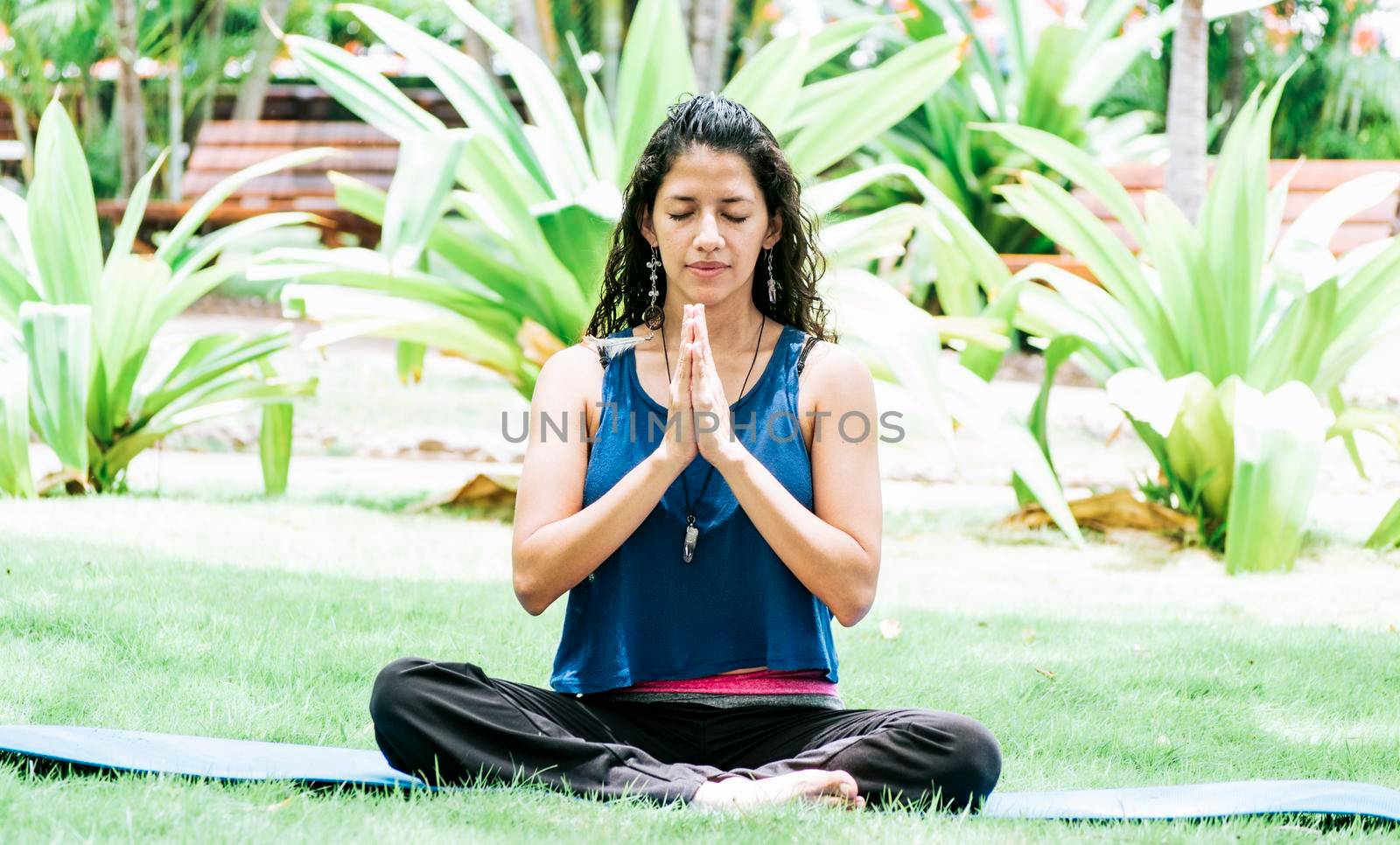 A girl sitting doing meditation yoga outdoors, Woman doing yoga outdoors, a young woman doing yoga with closed eyes.