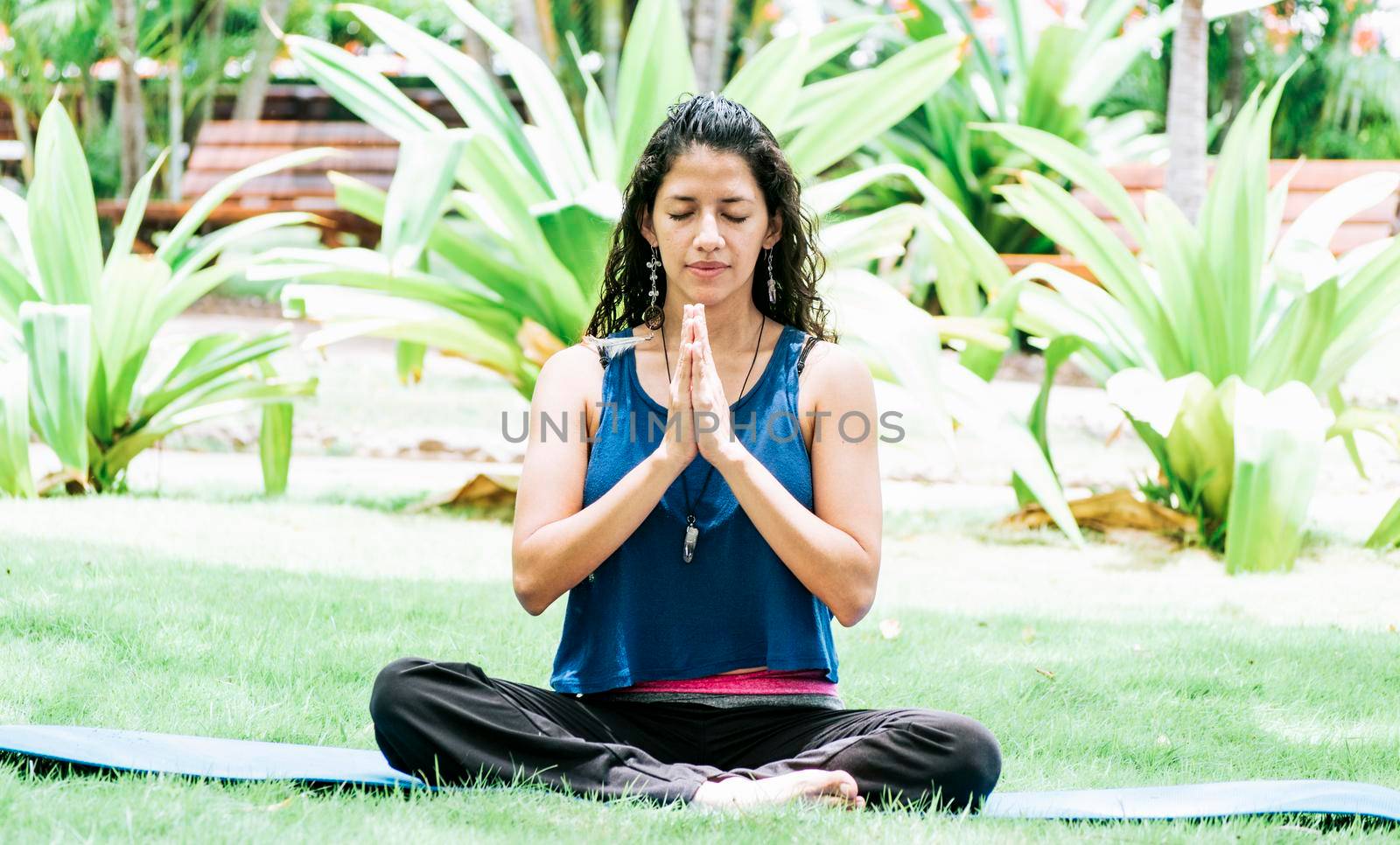 A girl sitting doing meditation yoga outdoors, Woman doing yoga outdoors, a young woman doing yoga with closed eyes. by isaiphoto