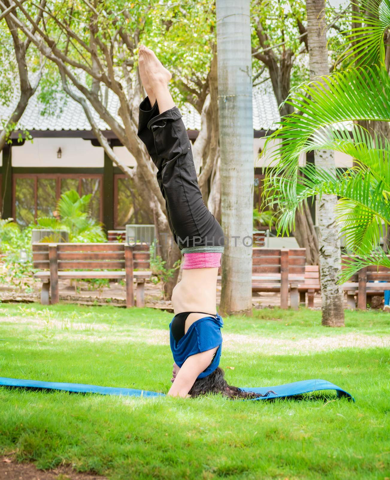 Girl doing headstand yoga, woman doing yoga outdoors lifting feet up, girl doing yoga with both legs up by isaiphoto