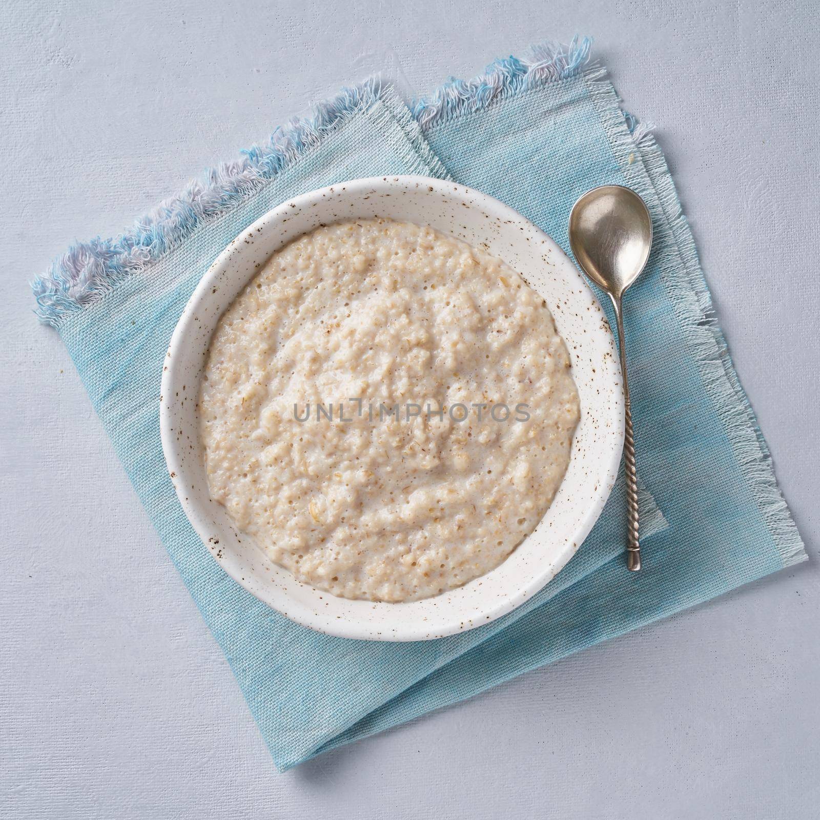 Oatmeal on blue light background. Milk porridge. Vegan food. Top view. Healthy diet breakfast