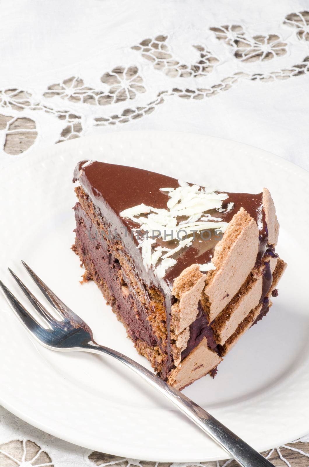 Slice of chocolate cake decorated with white chocolate flakes. From the series "French Desserts"