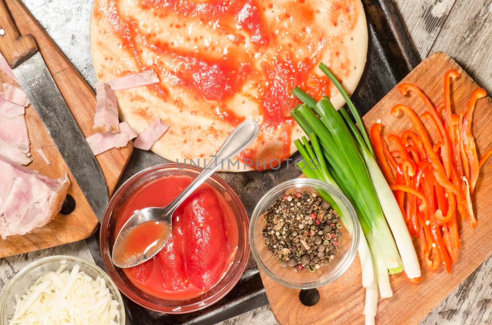 Homemade pizza on baking tray and Ingredients for cooking. From the series "Making homemade pizza"