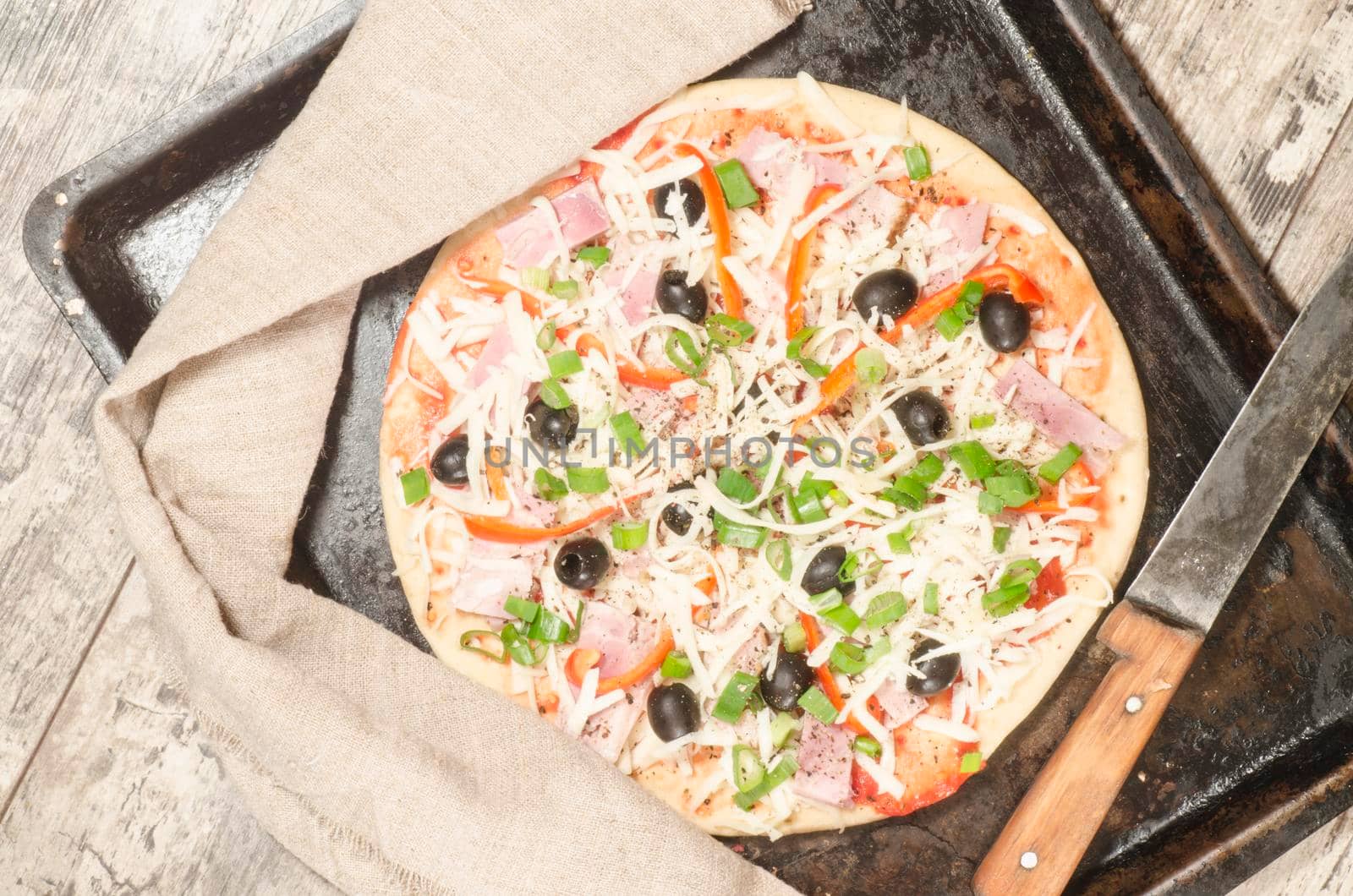 Homemade pizza on baking tray and Ingredients for cooking. From the series "Making homemade pizza"