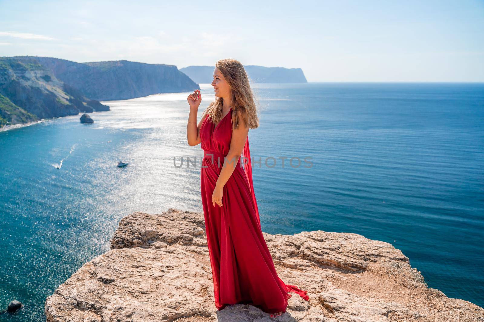 A woman in a red flying dress fluttering in the wind, against the backdrop of the sea. by Matiunina