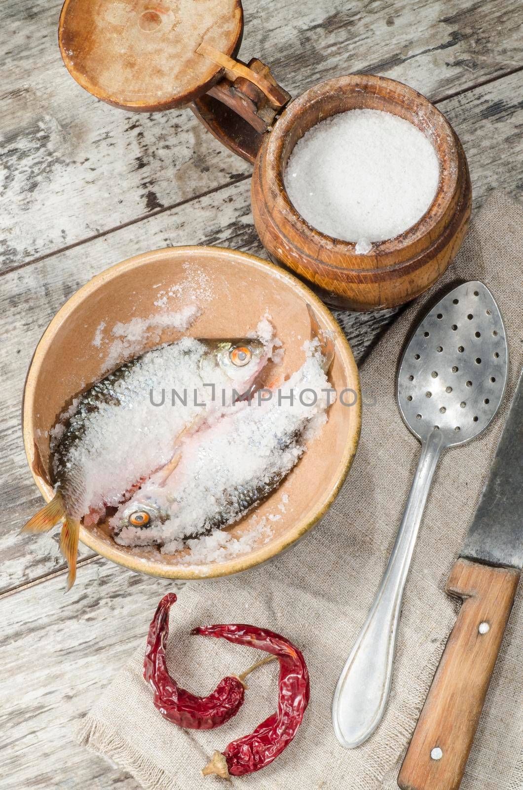 Two roaches fish in ceramic bowl with salt., near the old cutlery. From the series "Still Life with fresh fish"