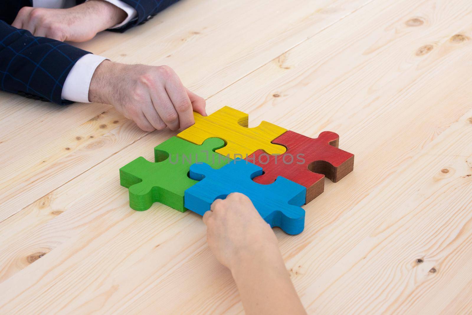 Business people helping in assembling puzzle, cooperation in decision making, team support in solving problems and corporate group teamwork concept, connecting pieces
