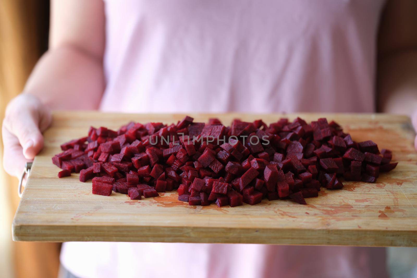 Woman is holding diced beetroot on wooden board. Cooking vegetarian food and the benefits of beetroot concept