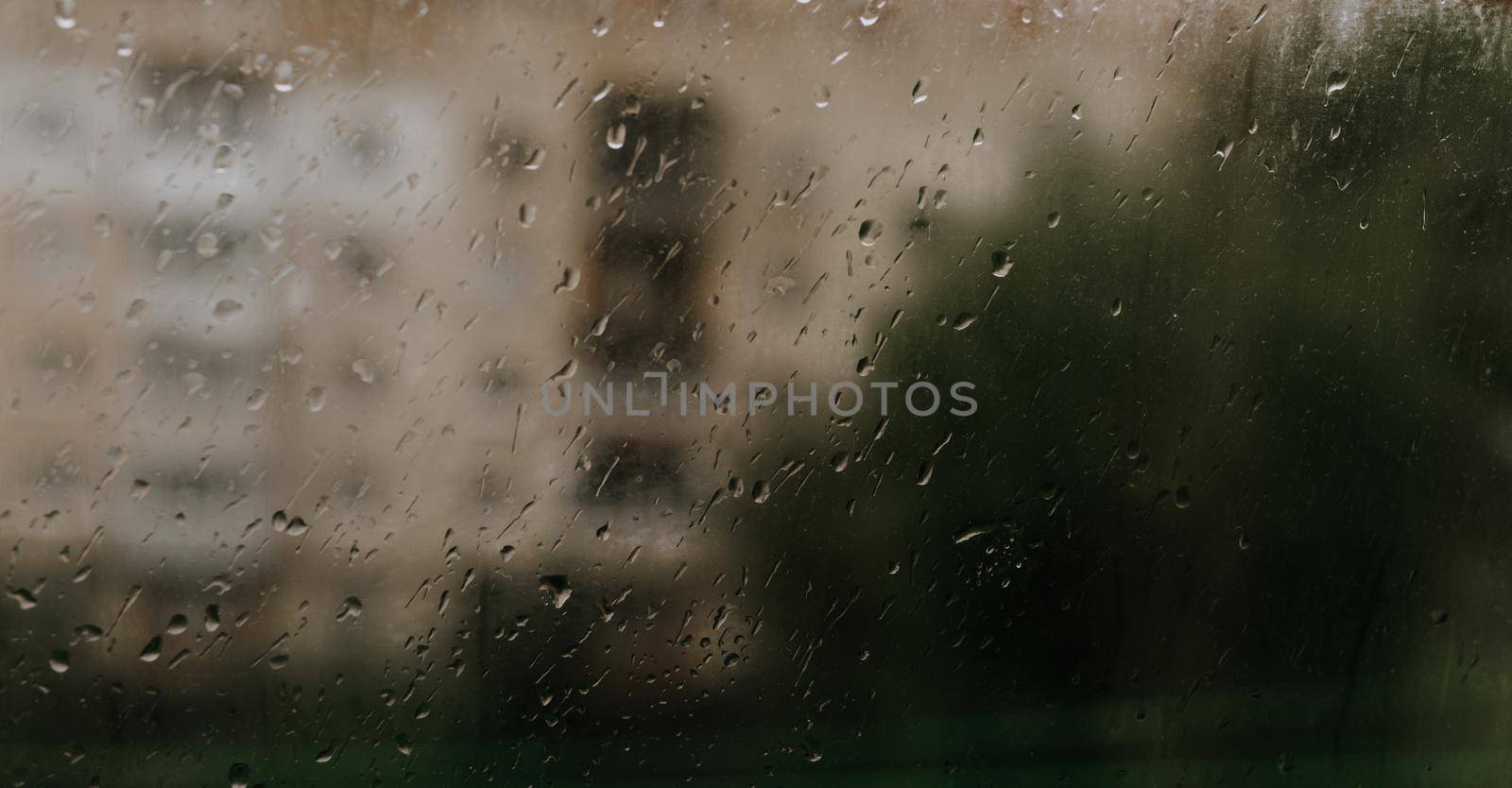 drops of rain water on the glass. drops collected on the window against the background of multi-storey buildings.