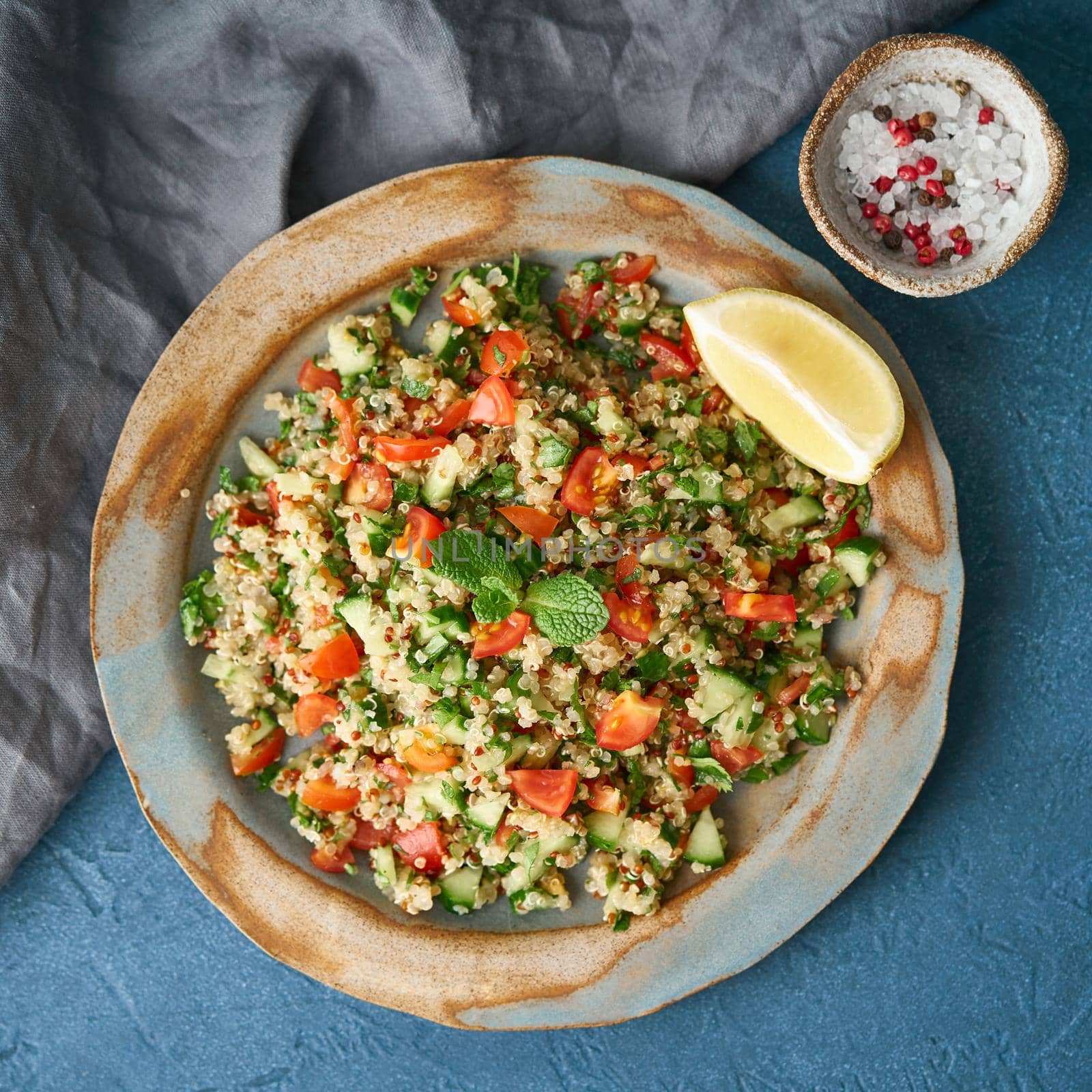 Tabbouleh salad with quinoa. Eastern food with vegetables mix on dark table, vegan diet. Top view