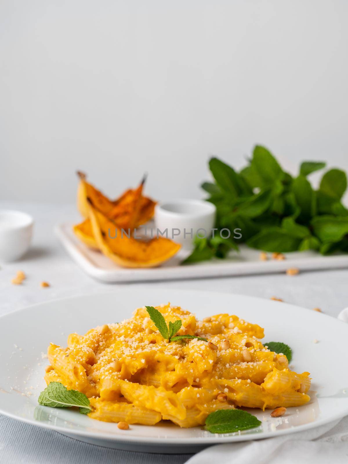 Pumpkin pasta penne with thick creamy sauce of baked squash and parmesan, side view, vertical