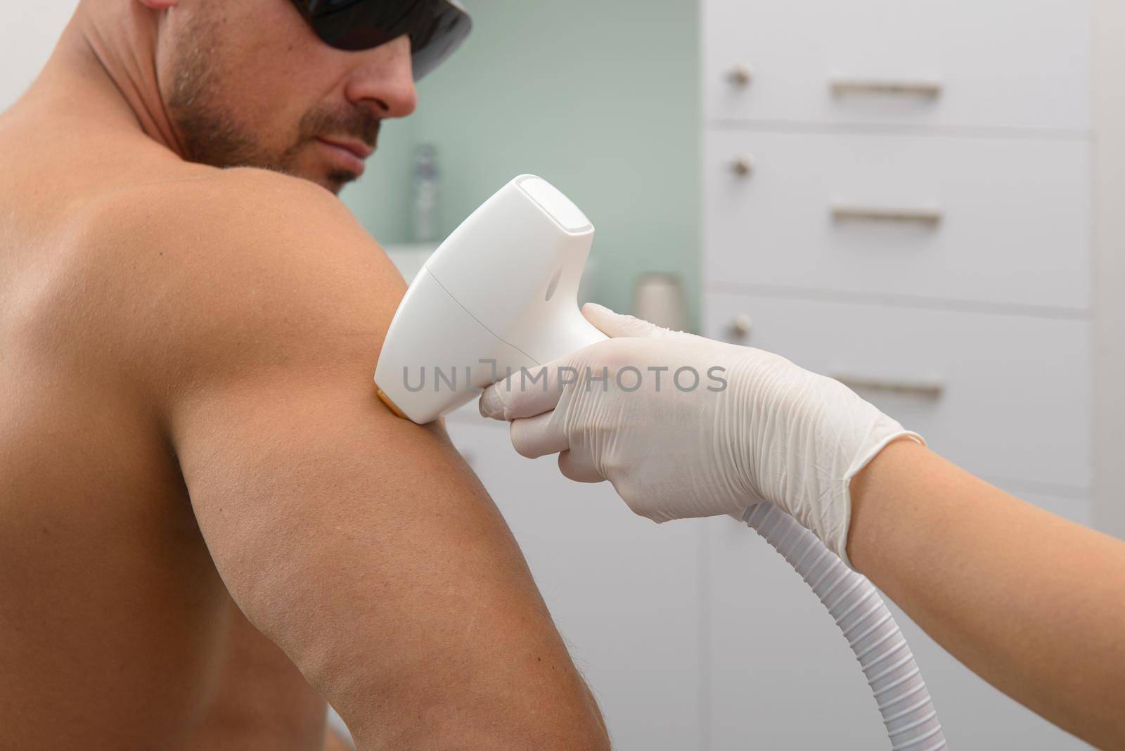 Laser hair removal on mans forearm. therapist in a pink t-shirt