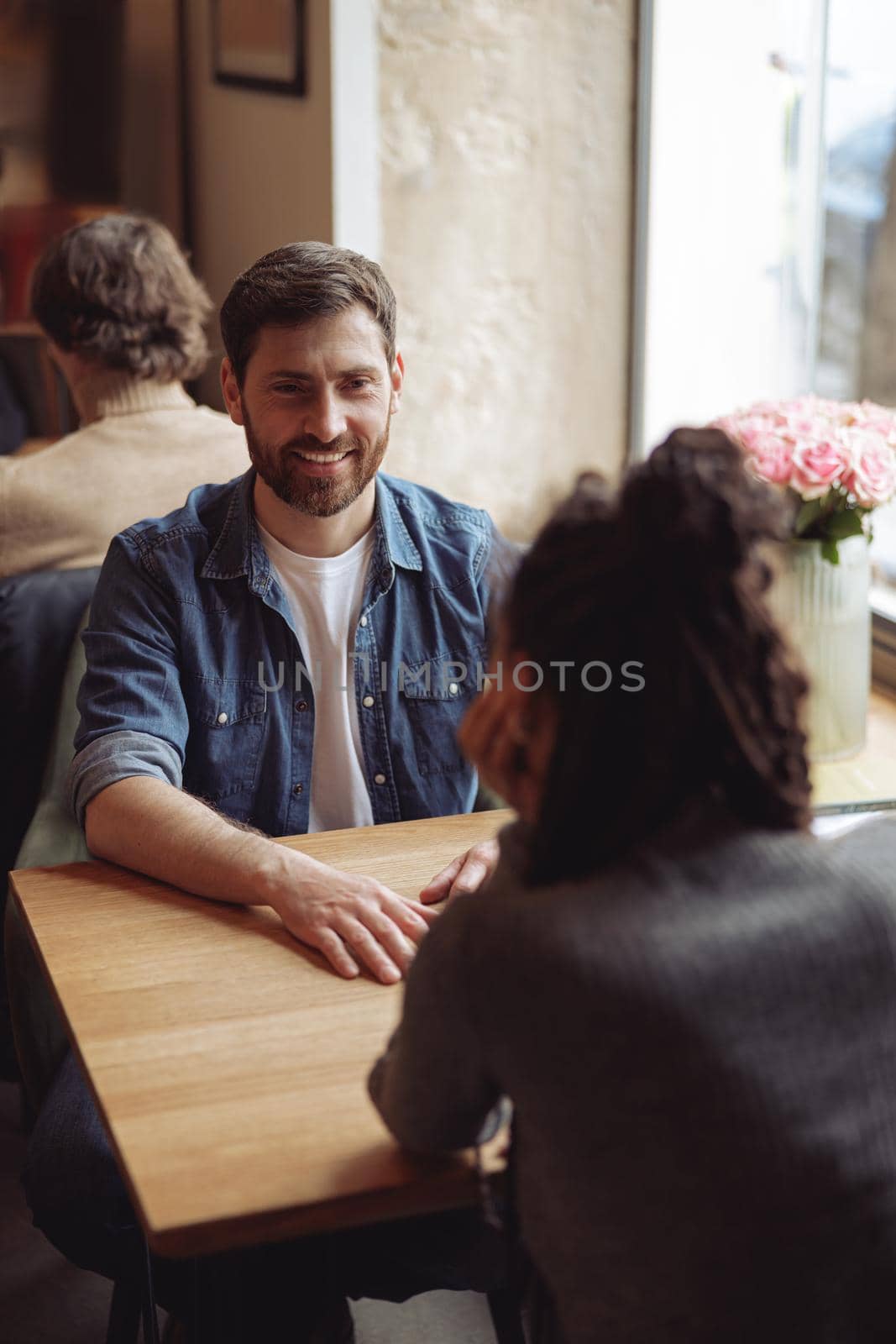 Handsome happy man smiling and sitting at table in cafe with friend. Caucasian male at date. by Yaroslav_astakhov