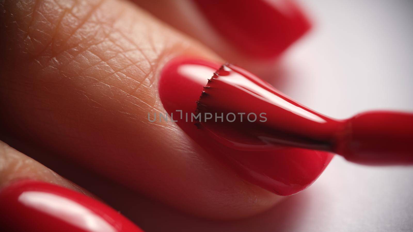 Manicurist paints nails with red gel polish. Application of nail polish. Manicured red nails concept