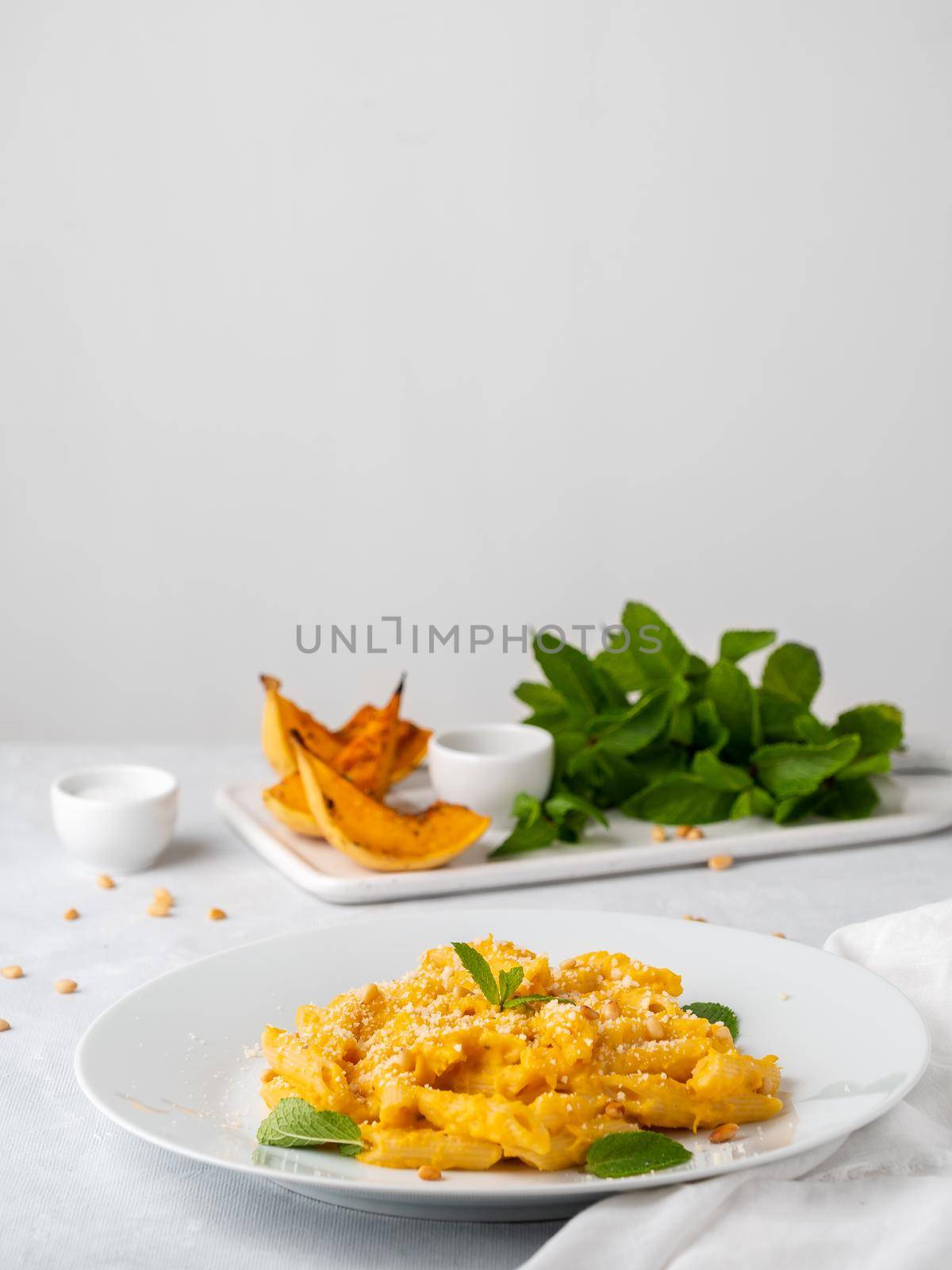 Pumpkin pasta penne with thick creamy sauce of baked squash and parmesan, side view, vertical