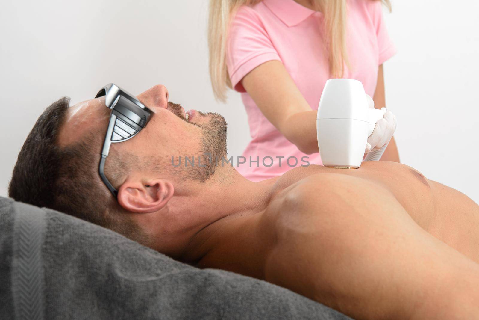Laser hair removal on mans chest. man in a goggles. by Ashtray25