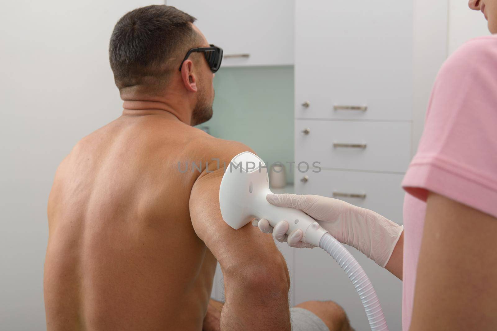 Laser hair removal on mans forearm. Doctor and patient in clinic. by Ashtray25