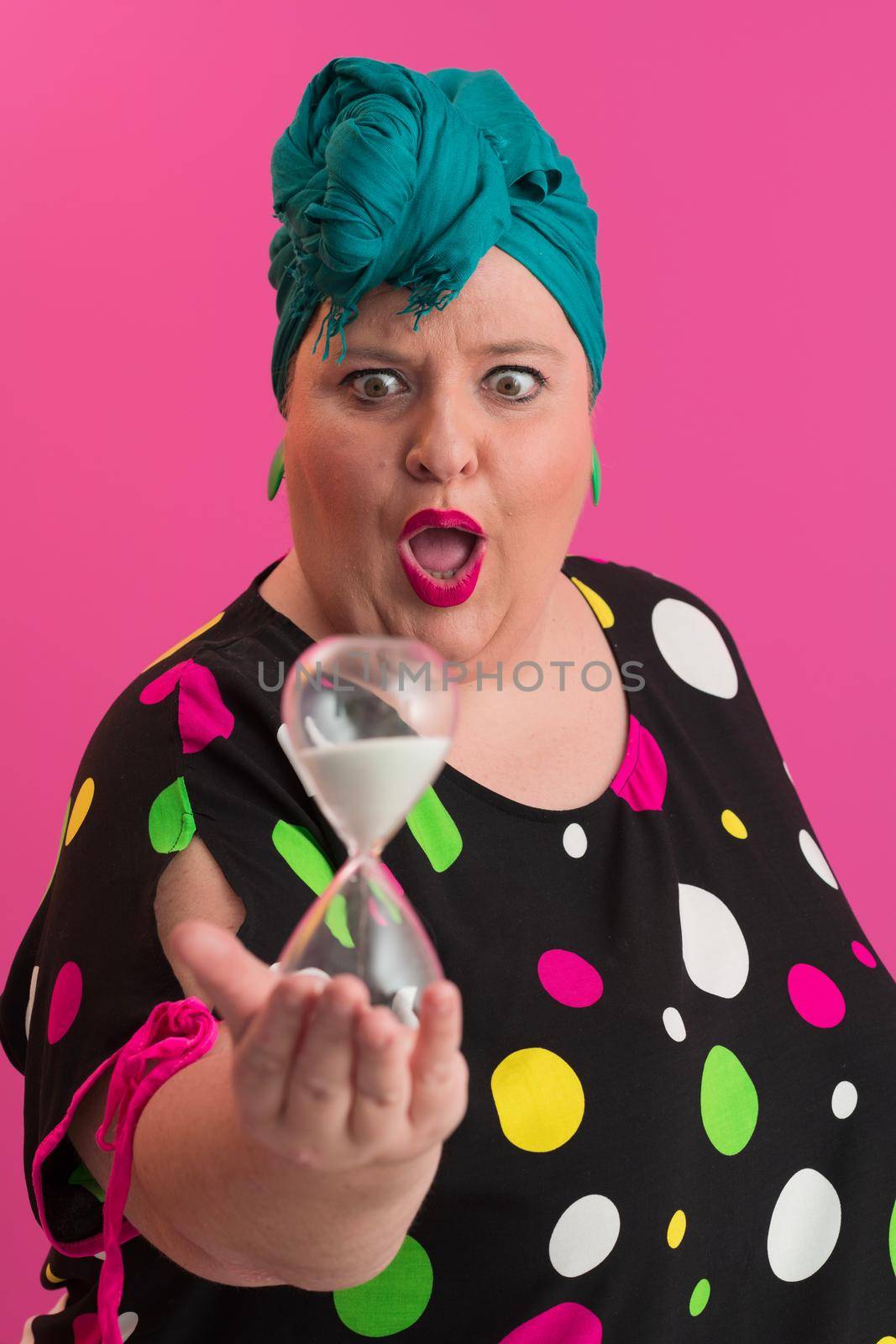 Portrait of plus size young lady smiling hands holds sand clock isolated on pink color background. High quality photo