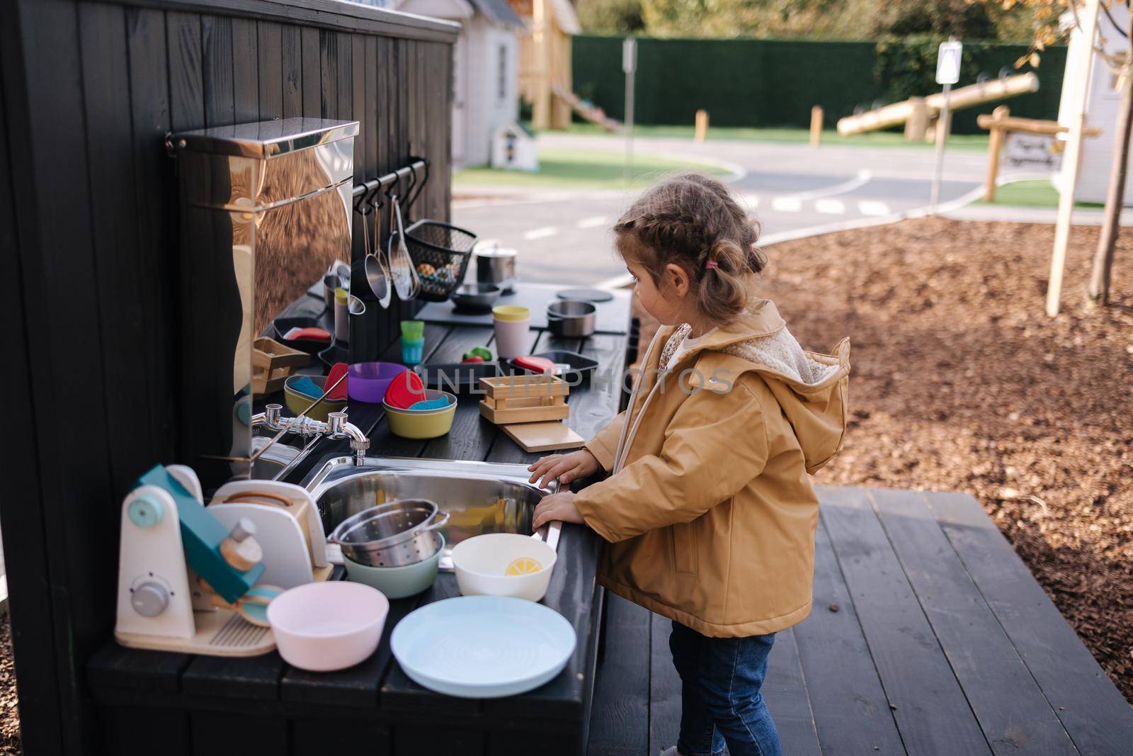 Adorable little girl playing in toy kitchen outdoors. Cute three year old girl have fun in kids city.