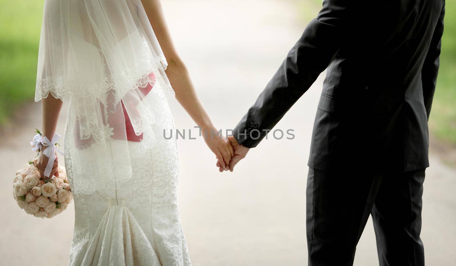 Bride and groom hold hands from back