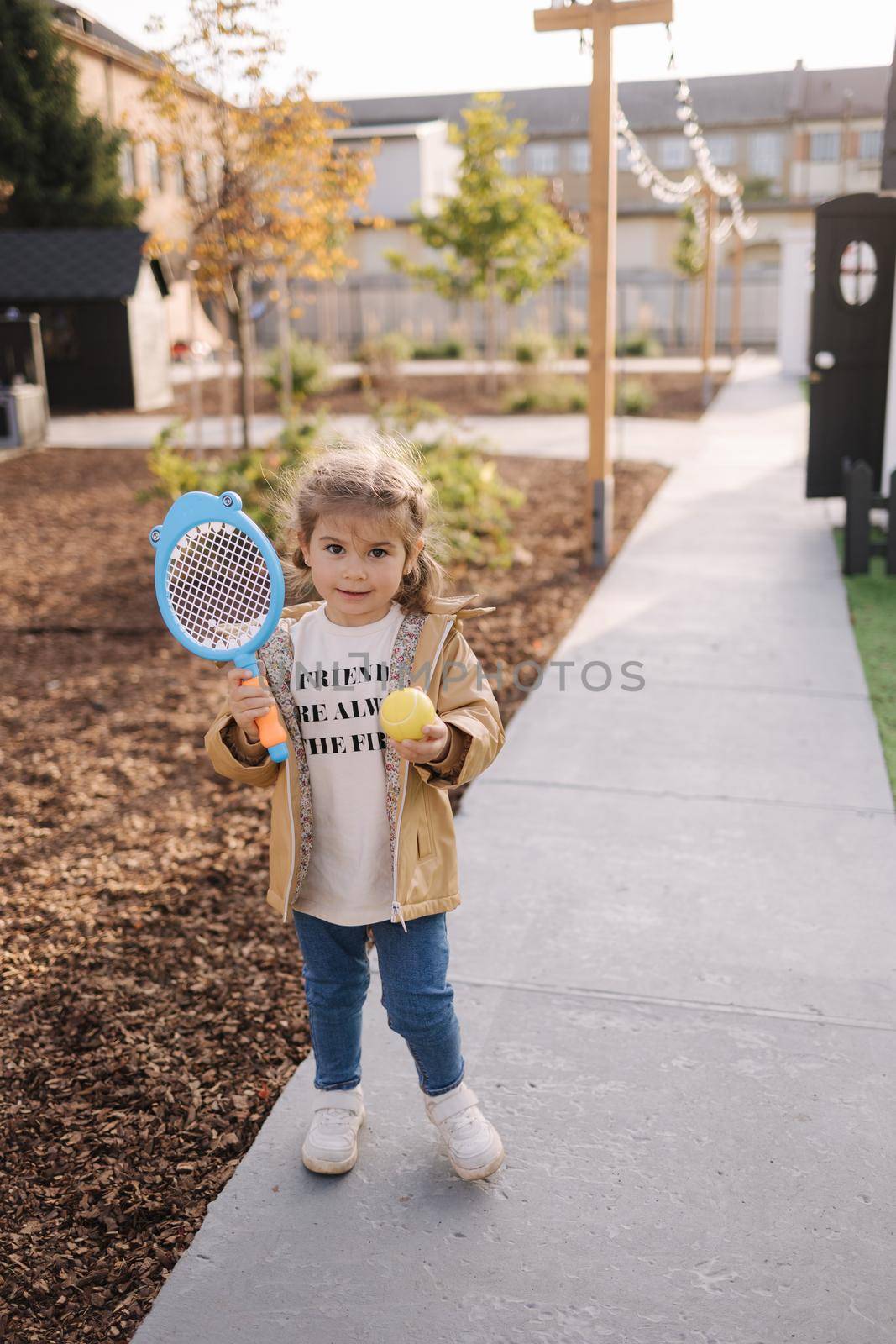 Cute little girl playing badminton in little kids city. Toy city for children.