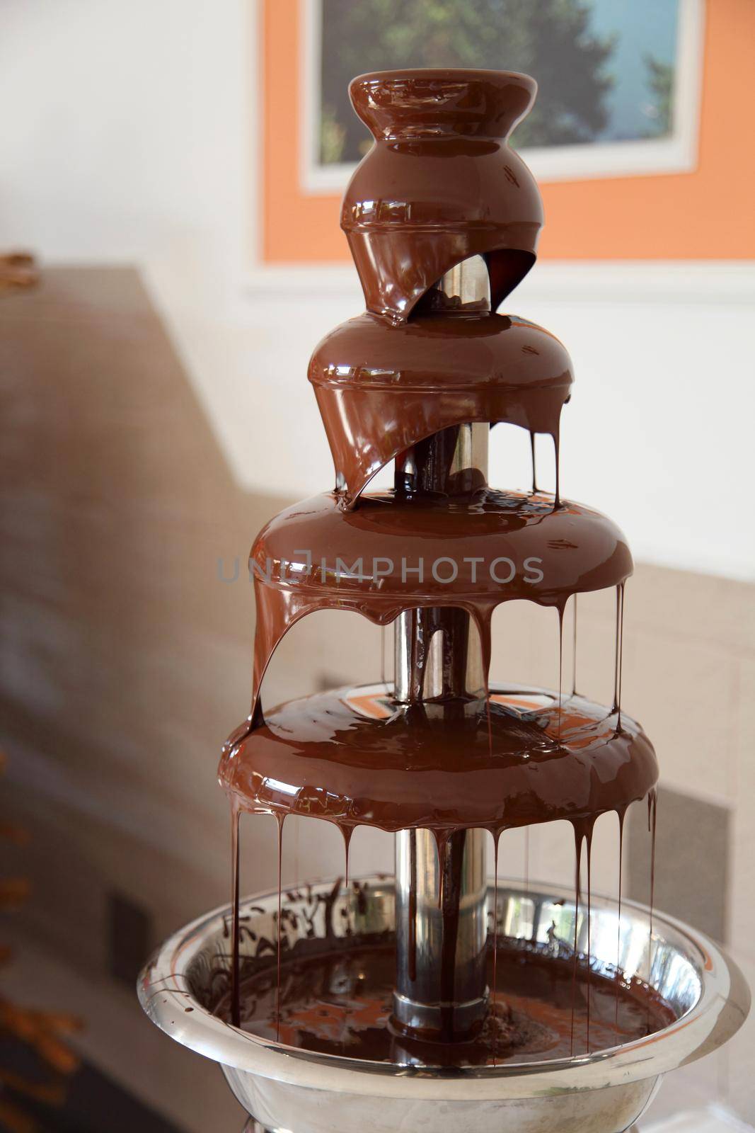 Chocolate fondue fountain with marshmallow being dipped.