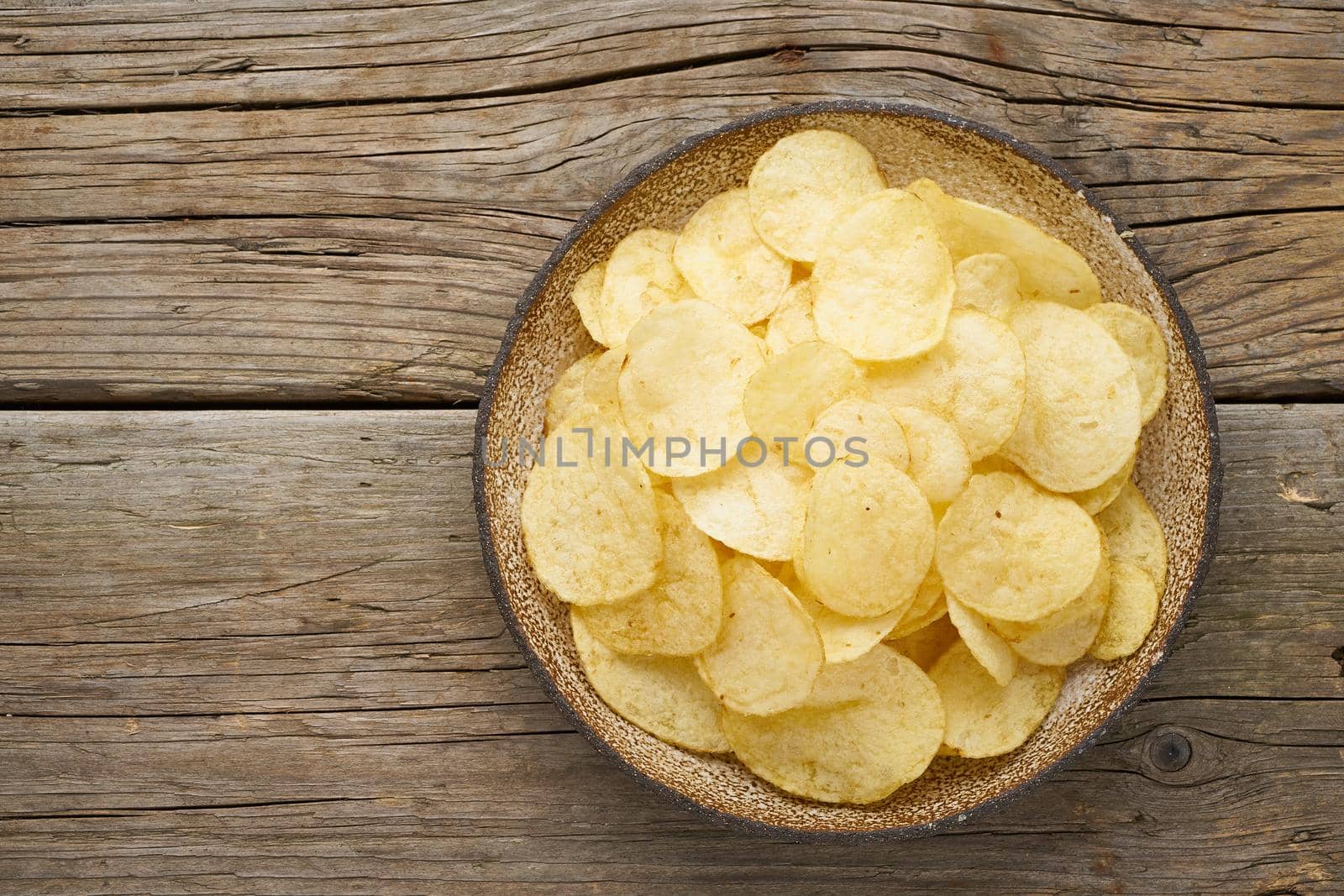 crisp in bowl, wooden background, top view
