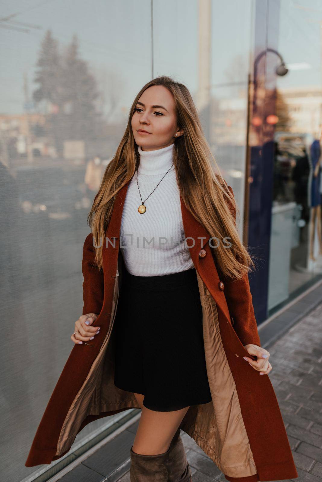 woman in autumn clothes walks on street background shop windows by AndriiDrachuk
