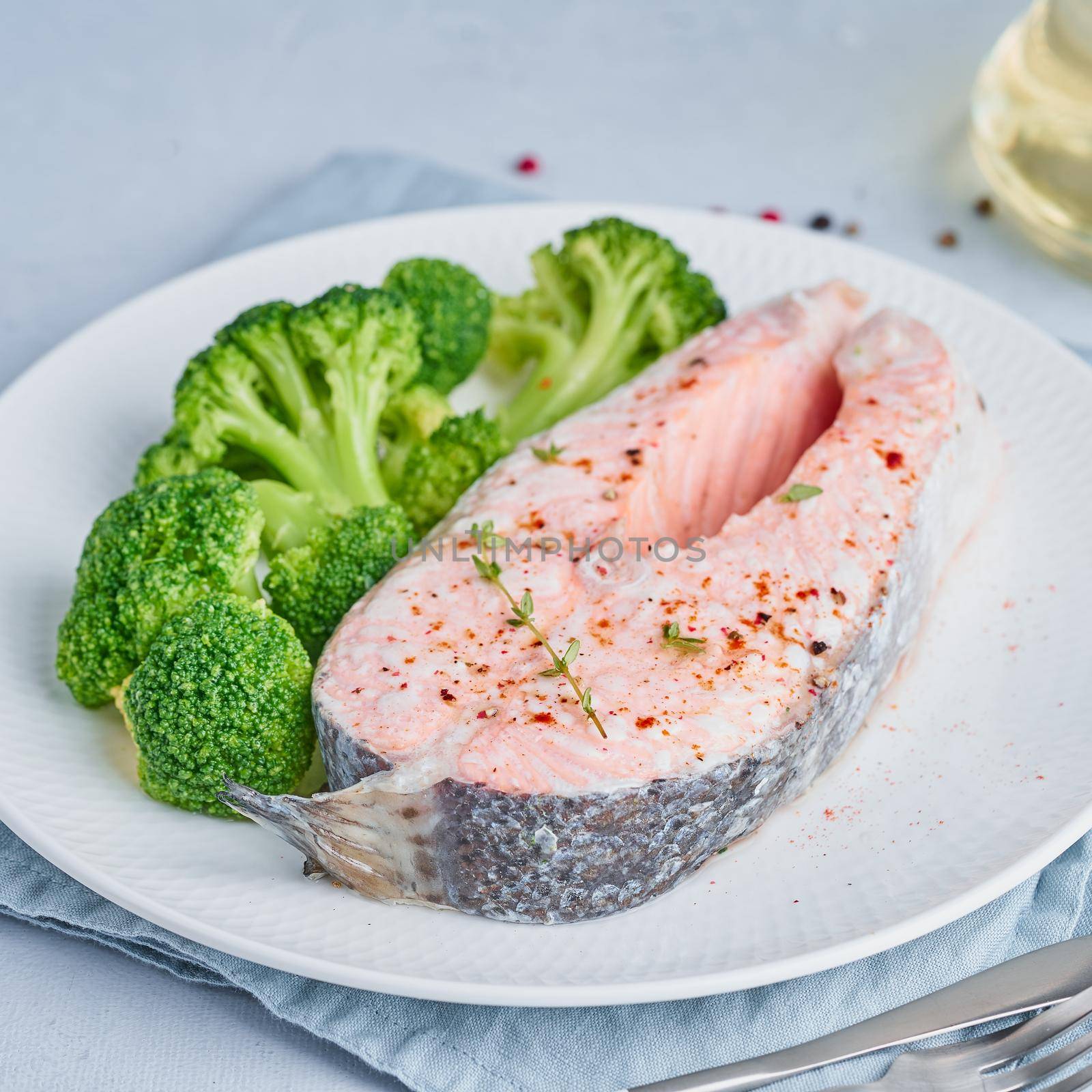 Steam salmon, broccoli, paleo, keto or fodmap diet. White plate on blue table, side view, close up