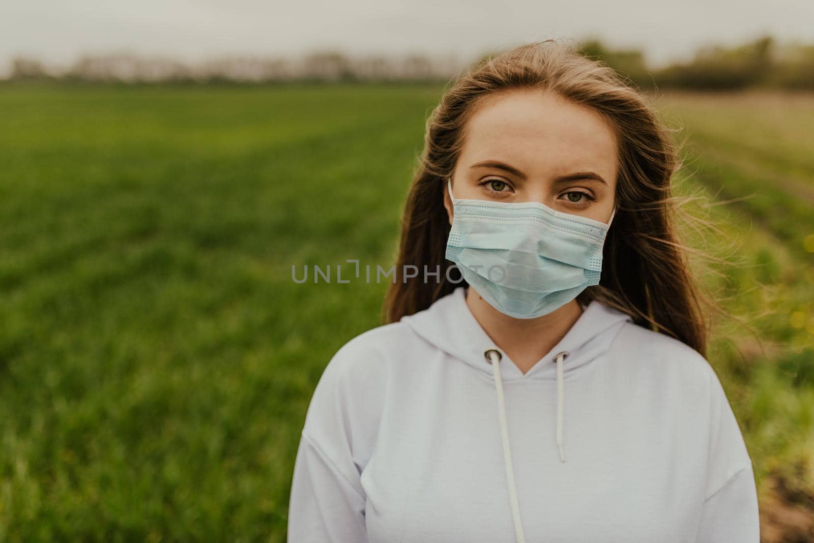 Young blond European woman in a protective mask outdoors.