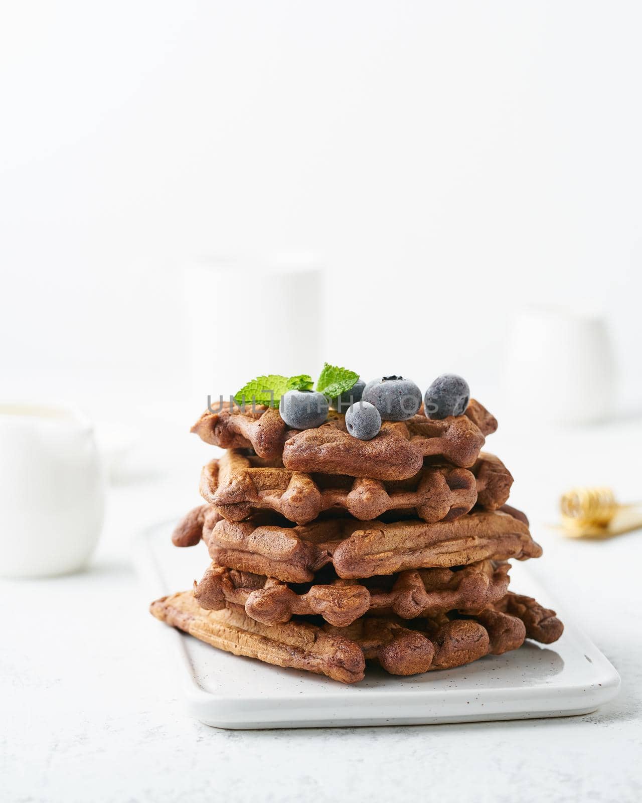 Chocolate banana waffles with blueberry on a white table. Side view, vertical
