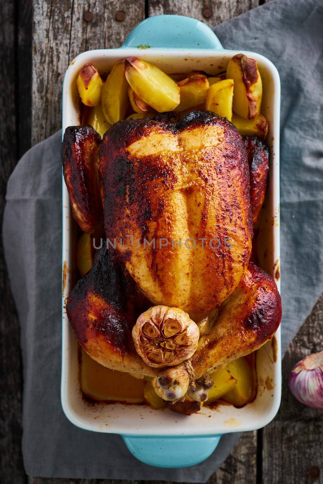 Baked whole chicken in blue casserole on dark gray old wooden table by NataBene