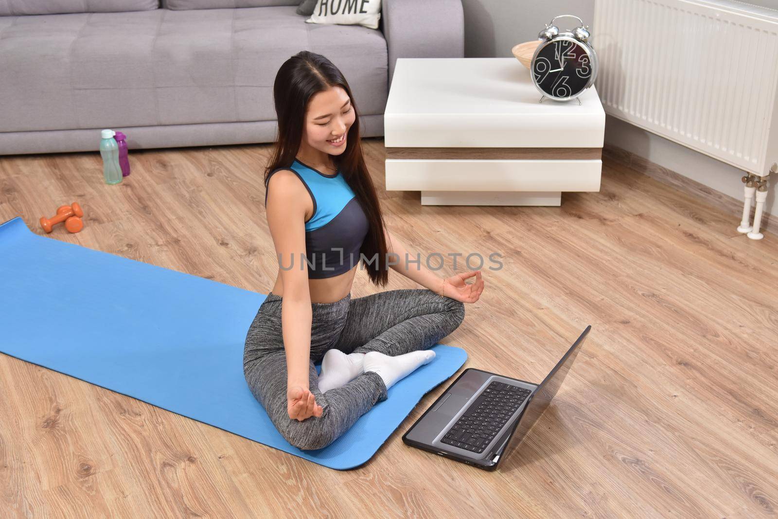 Young asian woman making yoga at home. Carantin and hobby. Home isolation. Online training. Soft focus