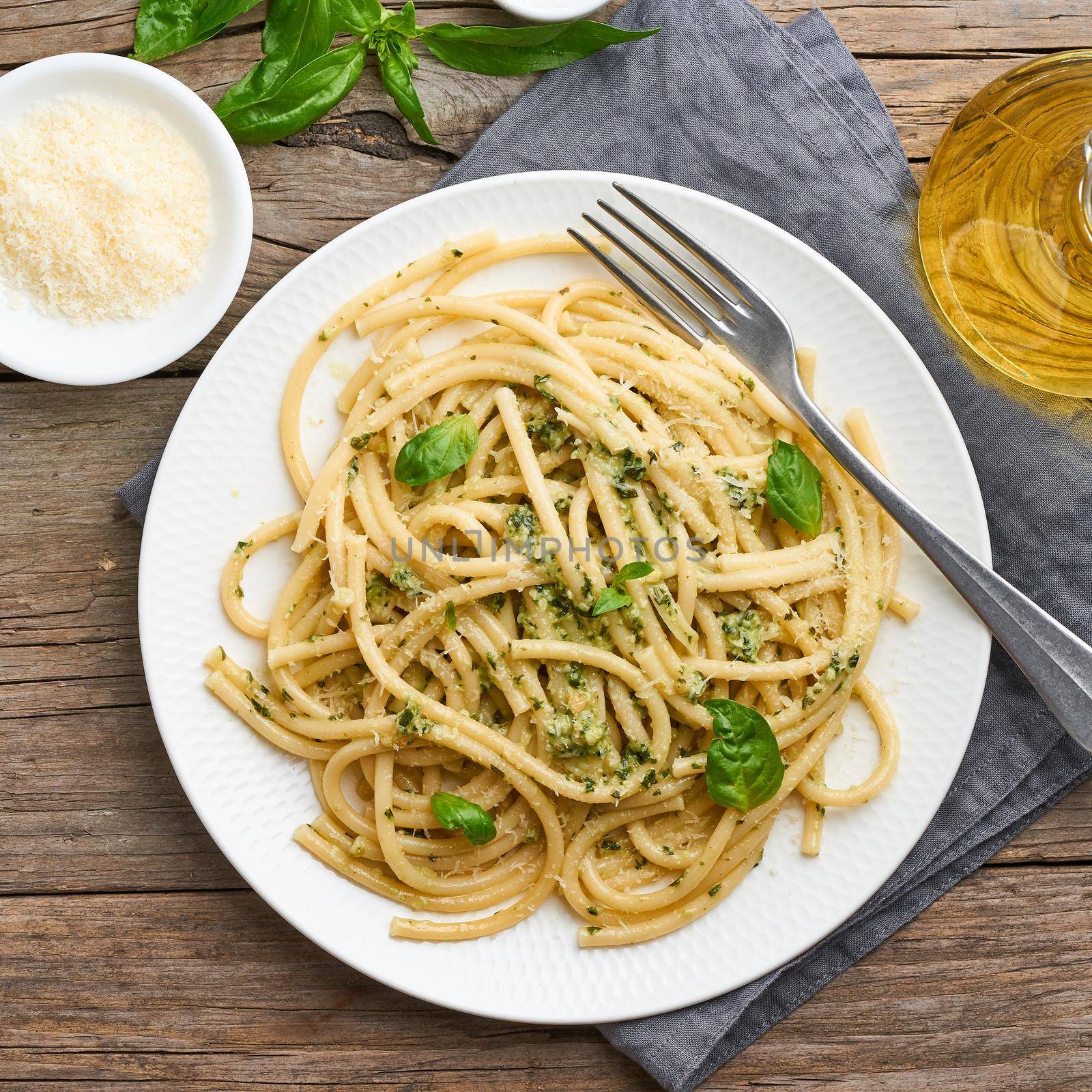 Pesto spaghetti pasta with basil, garlic, pine nuts, olive oil. Rustic table by NataBene