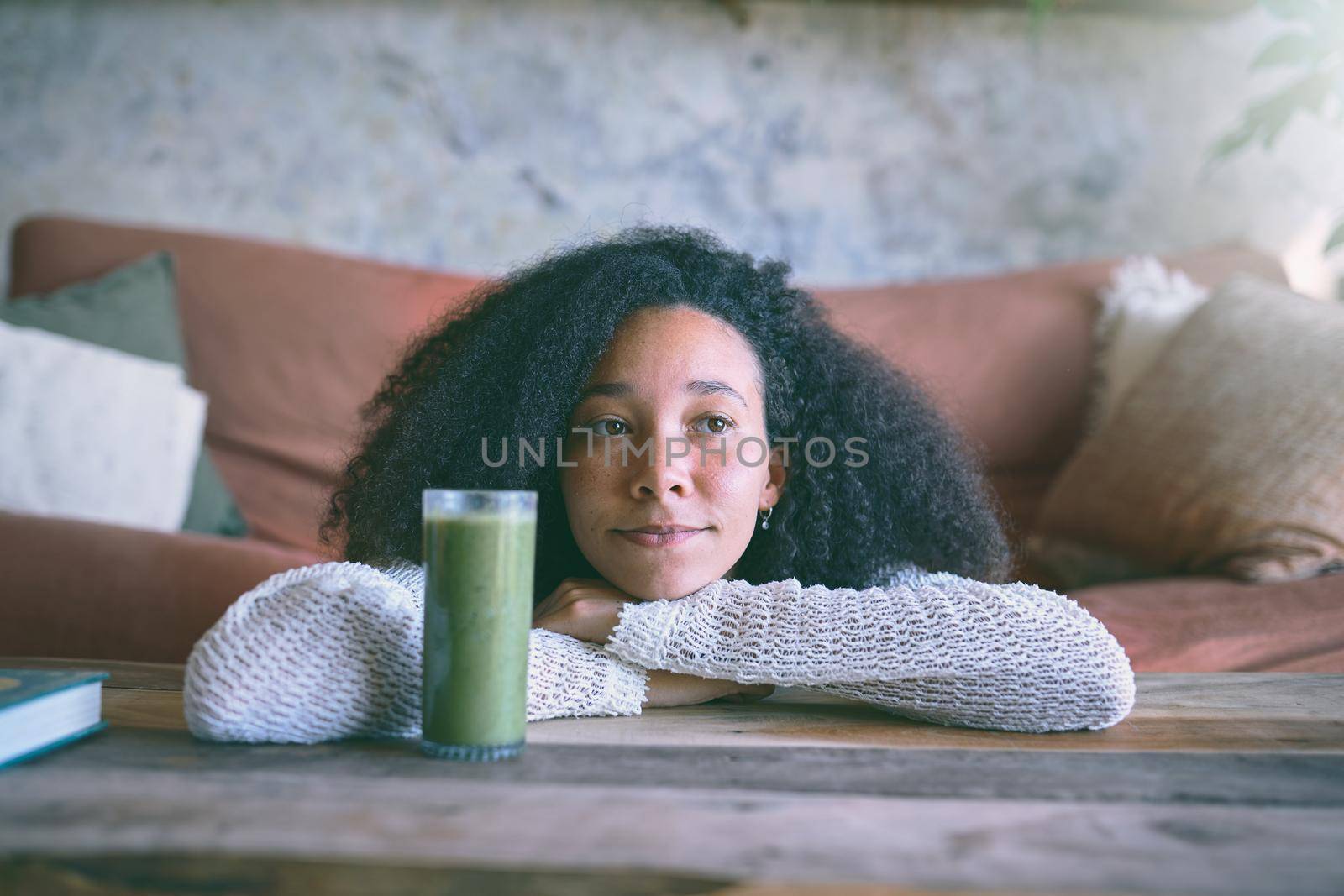 Beautiful girl daydreaming in her lounge with her healthy smoothie