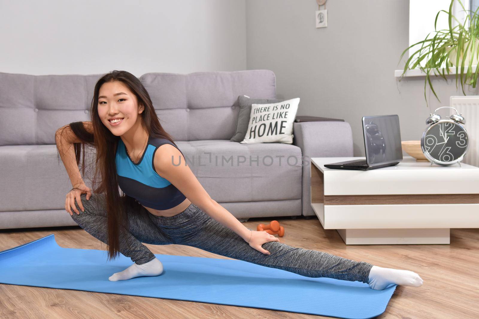 Young asian woman making yoga at home. Carantin and hobby. Home isolation. Online training. Soft focus