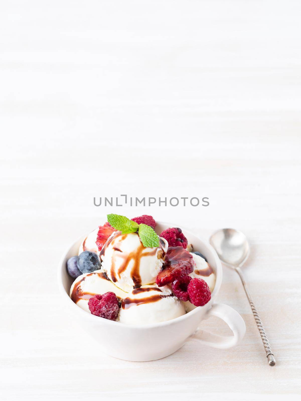 Balls of vanilla ice cream in mug with raspberry and blueberries by NataBene