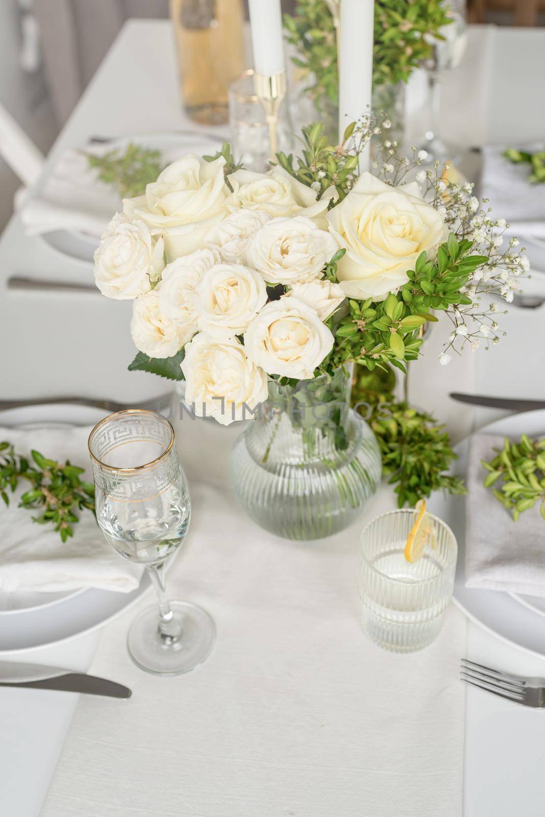 Wedding table set up in taditional style with roses grass and greenery. Close up of white roses bouquet