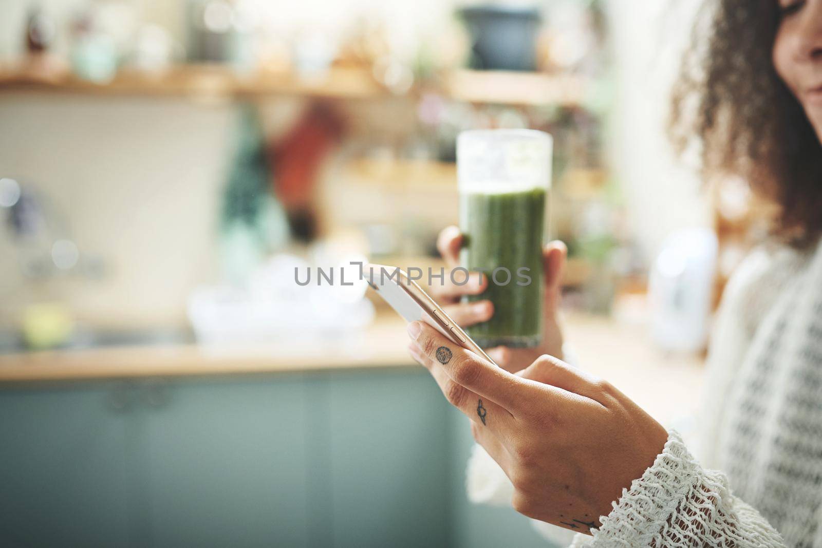 Beautiful young girl browsing online while enjoying her healthy green smoothie